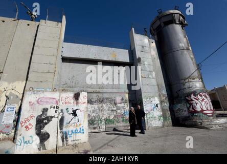 Bethlehem, West Bank. 23rd Dec, 2019. Palestinians stand beside an Israeli guard tower in the separation wall in the biblical town of Bethlehem, West Bank, on Monday, December 23, 2019. A new art work titled 'Scar of Bethlehem' by graffiti artist Banksy, shows a nativity scene in front of the Israeli separation barrier, is displayed at his Walled-Off Hotel nearby. Photo by Debbie Hill/UPI Credit: UPI/Alamy Live News Stock Photo