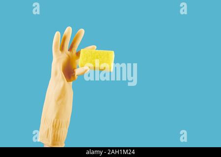 Housewife in yellow rubber glove holding kitchen soap , isolated on blue Stock Photo