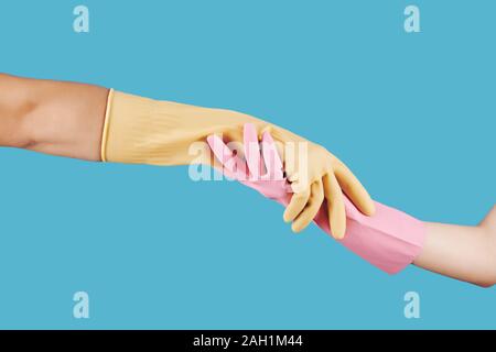 People in rubber gloves holding hands against blue background, helping hand concept Stock Photo