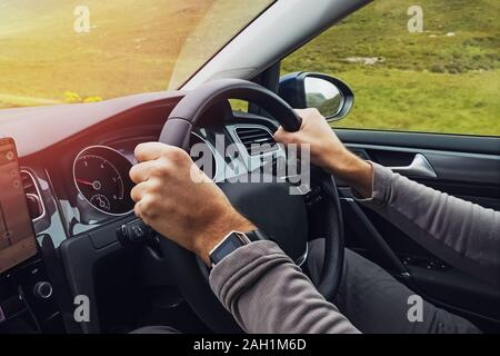 Man driving right hand car. Close-up shot of man's hands holding steering wheel. Travelling, renting a car abroad. Stock Photo
