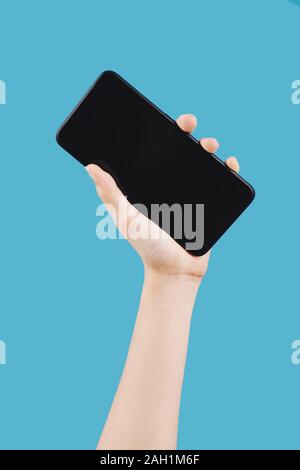 Female hand holding big screen smartphone against blue background Stock Photo