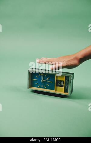 Man holding hand over vintage alarm clock, isolated on green Stock Photo