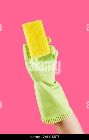Gloved hand of housewife cleaning with kitchen soap, isolated on pink Stock Photo