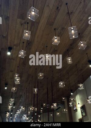 Transparent cube lamps hanging on wooden ceiling in a store. Stock Photo