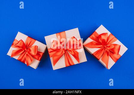 Three cardboard gift boxes with bows on blue background. Stock Photo