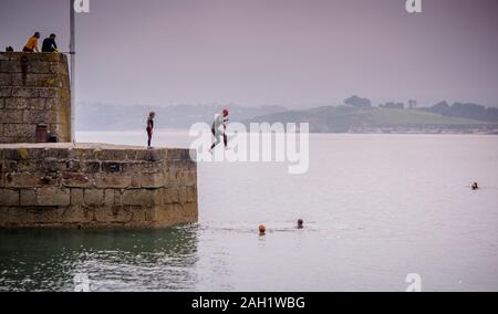 Swimmers jumping from the quay into the sea at Polkerris in Cornwall, UK. Stock Photo