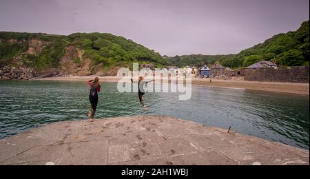 Swimmers jumping from the quay into the sea at Polkerris in Cornwall, UK. Stock Photo