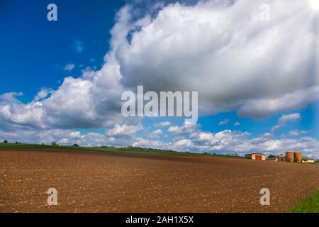 Bavarian rural landscape with plowed field and farm houses in background on a bright spring day Stock Photo