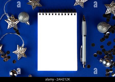 Christmas, winter composition. Notebook with isolated white page, open diary, sketch book mock-up scene on blue surface. Stock Photo