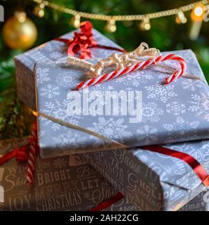 Packed Christmas presents and decoration with a christmas tree in the background. Stock Photo