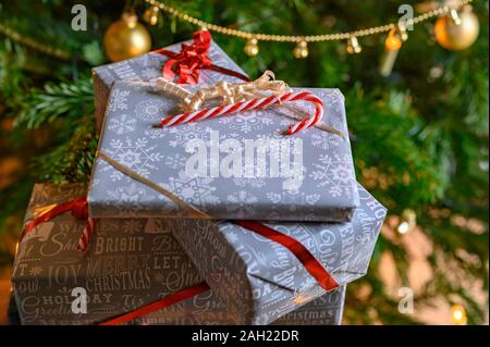 Packed Christmas presents and decoration with a christmas tree in the background. Stock Photo