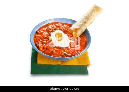 chili con carne  served with small soft tortilla recipe is the perfect one pot meal to warm up. decoration is white cream with pickled green tomatoes Stock Photo