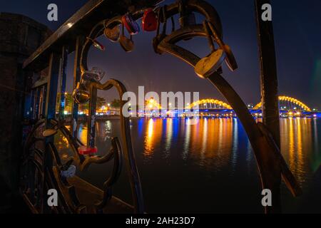 Close up of locked padlocks are placed on the Love Bridge as symbol of love. Nigtht view of the Dragon Bridge over the Han River in Da Nang, Vietnam Stock Photo