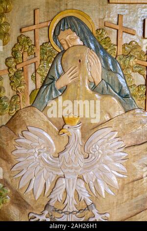 Tylicz, Poland. 2019/8/8. A wooden relief sculpture of the Virgin Mary embracing the wounded Polish nation. The Sanctuary of Our Lady of Tylicz. Stock Photo