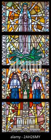 Stained-glass window depicting Our Lady of Fátima with three shepherd children - Lúcia, Jacinta and Francisco. The Sanctuary of Our Lady of Tylicz. Stock Photo