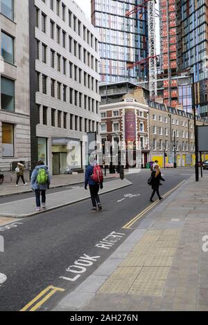 People with rucksacks cross the road at Finsbury Square and Sun Street to walk to Shoreditch in the City of London EC2 England UK  KATHY DEWITT Stock Photo