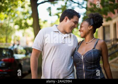 Happy young couple walking side by side down an urban street Stock Photo