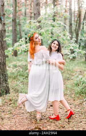 Funny two beautiful girls bridesmaids dance in the forest. Two ...