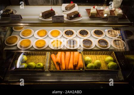 Various cakes and fruits are on display in the showcase. Stock Photo