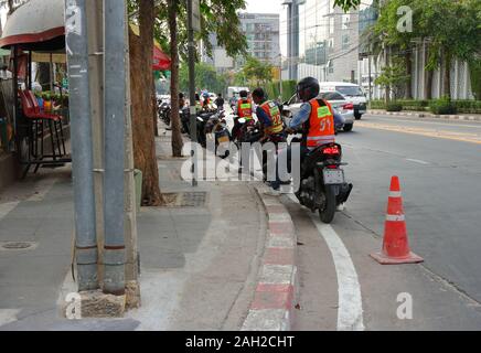 Bangkok, Thailand-December 23, 2019 : Group of motorcyclists get ready on pillions waiting for passengers at motorcycle taxi queue. Stock Photo