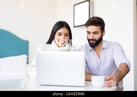 A man and a woman work together on a laptop. They are discussing something for their apartment. They are looking for something important on the Intern Stock Photo