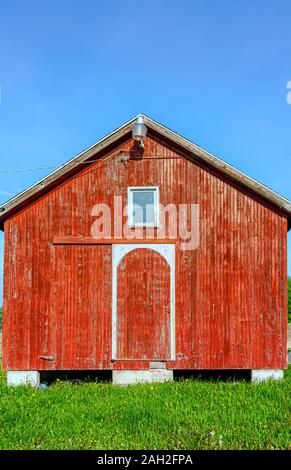 A red barn with weathered wooden exteriors illuminated by strong morning sunlight. Stock Photo