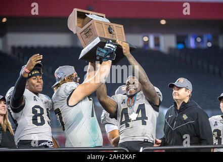 Tampa, FL, USA. 23rd Dec, 2019. (Right) UCF head coach Josh Heupel watches as the Gasparilla trophy is hoisted by L-R UCF tight end Anthony Roberson (89), UCF offensive lineman Jake Brown (77) and UCF linebacker Nate Evans (44) during awards ceremony of the Bad Boy Mowers Gasparilla Bowl between UCF Knights and the Marshall Thundering Herd. Central Florida defeated Marshall 48-25 at Raymond James Stadium in Tampa, FL. Romeo T Guzman/CSM/Alamy Live News