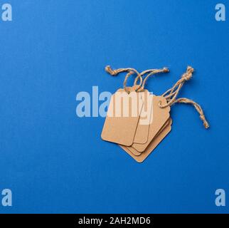 set of empty paper brown rectangular tags on a rope, price tags are on a blue trend background, top view Stock Photo