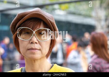 Candid portrait of mature Taiwanese woman of Chinese ethnicity in the city looking cool wearing a peaked leather cap. Stock Photo