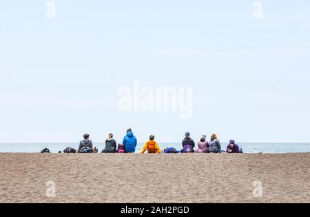 A group of people sitting on Rodeo Beach in the Marin Headlands, Golden Gate National Recreation Area, California, USA. Stock Photo