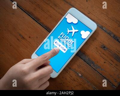 Flight booking online with smartphone. Top view finger touching on mobile phone for buying or booking air flight online airline ticket. Stock Photo