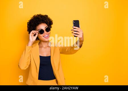 Portrait of positive cheerful girl enjoy journey vacation take photo on her smartphone real influencer concept wear stylish suit isolated over yellow Stock Photo