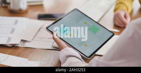Close-up view of young hard-working ui web designer working on her concept with tablet Stock Photo