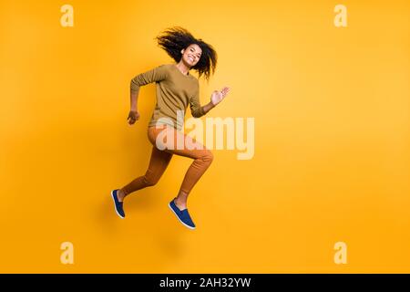Full length body size photo of cheerful positive beautiful attractive charming pretty girl wearing orange pants trousers running jumping towards empty