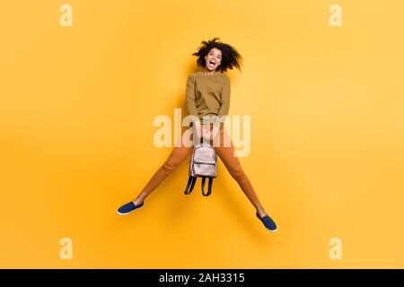 Full length body size photo of cheerful charming positive cute beautiful pretty sweet curly wavy youngster holding handbag with hands jumping with Stock Photo