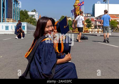 A group of female graduates of Mengly J Quach Education sits in front of the Royal Palace holding their diplomas in Phnom Penh, Cambodia. Stock Photo