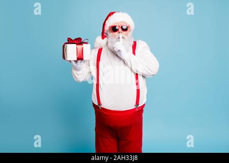 Hush its secret. Portrait of focused funny funky fat santa claus with big abdomen belly prepare gift for eve noel hold small giftbox wear red pants Stock Photo