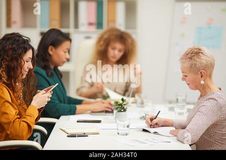 Horizontal shot of four beautiful businesswomen sitting together at office desk in board room working on business plan Stock Photo