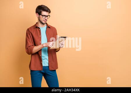 Portrait of his he nice attractive calm focused successful content brunet guy holding in hands reading digital e-book isolated over beige color pastel Stock Photo