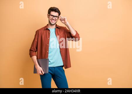 Portrait of his he nice attractive cheerful cheery successful content brunet guy holding in hands carrying laptop posing touching specs isolated over Stock Photo
