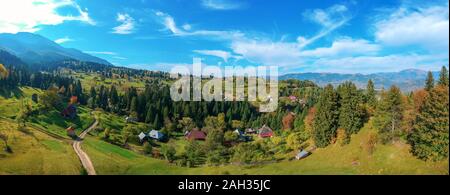 Aerial panoramic view of a rural region with farms, fields and the Carpathian mountain range in the background. Borsa, Maramures, Romania. Stock Photo
