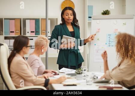 Elegant African American businesswoman making short month report at meeting, horizontal shot Stock Photo