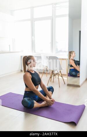 Young caucasian blonde woman practicing yoga, enjoying morning home workout in Lotus pose on meditation time, full length, isolated, over white studio Stock Photo