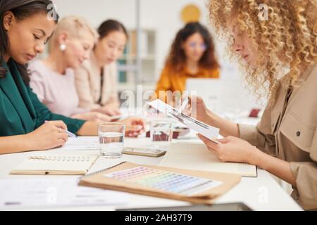 Team of fashion designers sitting togeher at office table in board room working on new collection, horizontal shot Stock Photo
