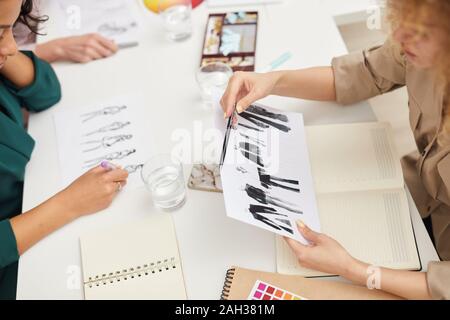 Horizontal high angle shot of unrecognizable fashion designers making and choosing clothes sketches Stock Photo