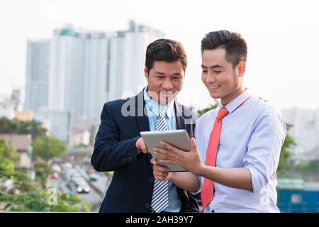 Young handsome businessmen discussing project on digital tablet computer outdoors Stock Photo