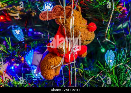 Soft reindeer toy hanging from Xmas Tree seen with tinsel and lights. Taken in Kings Lynn, Norfolk, UK on 23rd Dec 2019. Stock Photo