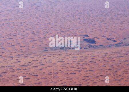 View from the air of round irrigation fields and farms surrounded by sand dunes in the desert in Saudi Arabia Stock Photo