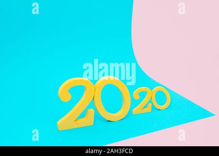 closeup of some yellow three-dimensional numbers forming the number 2020, as the new year, on a pink and blue background with some blank space around Stock Photo