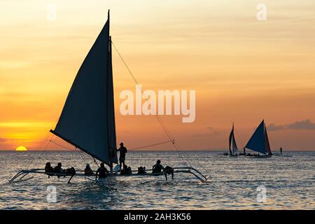 Boracay, Aklan Province, Philippines - January 30, 2018: Silhouettes of Philippine sailing boats carrying tourists on their daily sunset tours Stock Photo